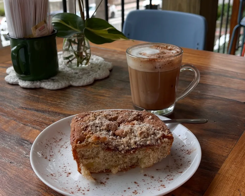 Fatia de bolo e café com leite numa mesa de madeira, num café da tarde no sítio
